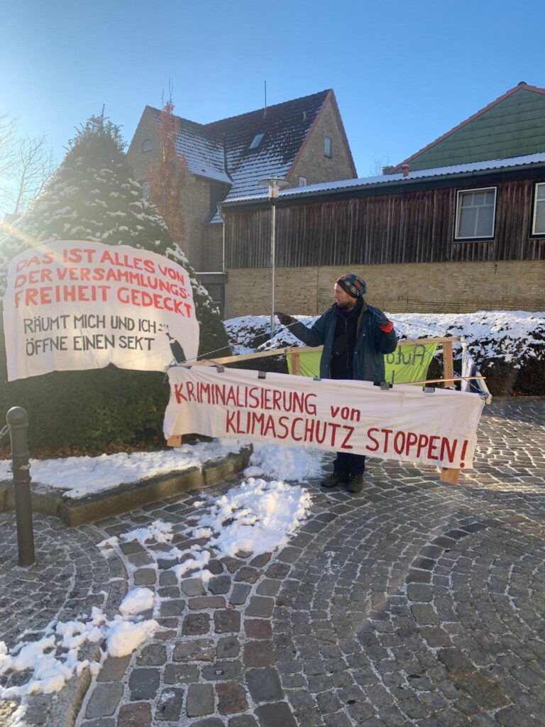 Mensch steht mit Gehzeug da "Kriminalisierung von Klimaschutz stoppen!" -